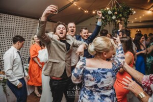 A bride and groom dance surrounded by wedding guests