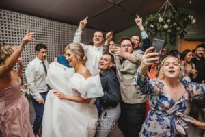 A bride and groom dance surrounded by wedding guests