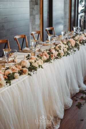 Pink and white flowers decorate the bridal table at a wedding reception