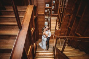 A bride and groom stand kissing on a wooden staircase at their Sydney wedding reception