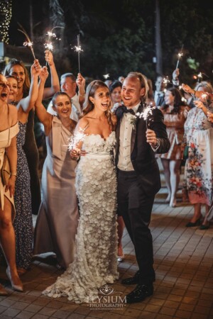 Newlyweds walk through wedding guests holding sparklers as they say farewell after the reception