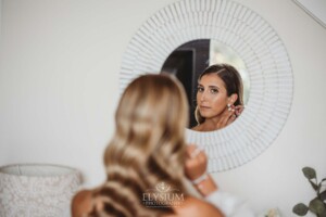 A bride reflected in a round white mirror does some final checks before the wedding