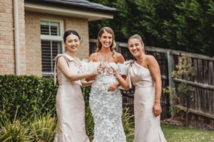 bride and bridesmaids stand on a green lawn before going to the wedding ceremony