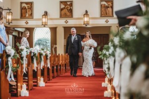 A bride walks with her father down the wedding aisle in the chapel of Loreto Normanhurst