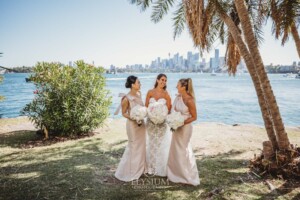A bridal party stand together on the shores of Sydney Harbour after the wedding ceremony