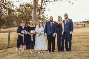 A bridal party stand on the lawn of Ottimo House at sunset