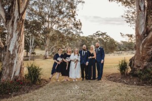 A bridal party stand on the lawn of Ottimo House at sunset