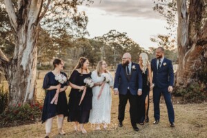 A bridal party stand on the lawn of Ottimo House at sunset