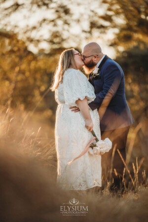 A bride and groom share a kiss on the hilltop behind Ottimo House after their wedding