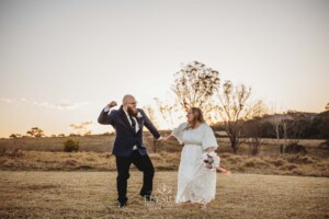 A bride and groom pump their fists in the air after their wedding at sunset