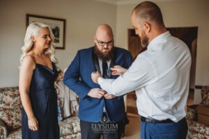 A groomsman helps the groom adjust his jacket as they get ready for the wedding