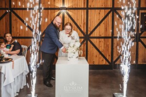 A bride and groom cutting their wedding cake surrounded by sparklers