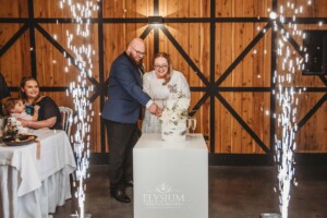 A bride and groom cutting their wedding cake surrounded by sparklers