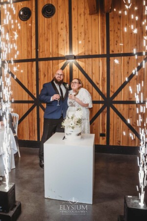 A bride and groom cutting their wedding cake surrounded by sparklers