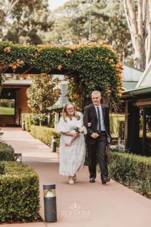 A bride walks with her father down the aisle towards her wedding ceremony