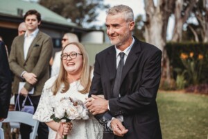 A bride walks with her father down the aisle towards her wedding ceremony