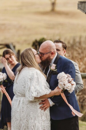 A bride and groom share a kiss at the start of their wedding ceremony