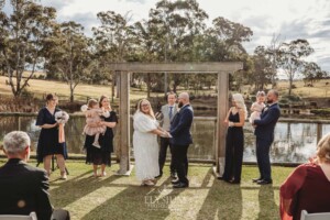 A bride and groom stand under a timber arbor at their Ottimo House wedding ceremony