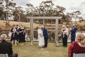 A bride and groom kiss under a timber arbor at their Ottimo House wedding ceremony