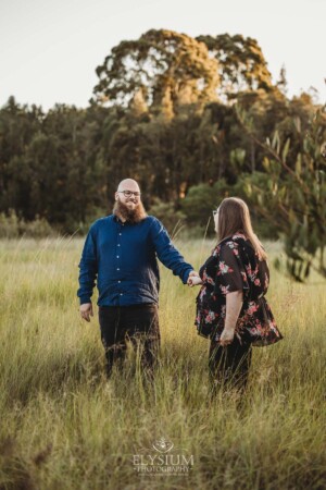 An engagement session with a couple in a grassy field at sunset