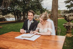 A bride and groom sign their marriage certificate during their outdoor wedding ceremony