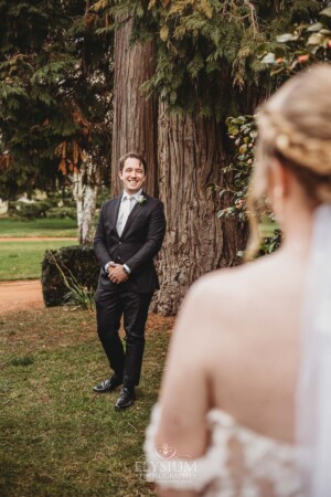 A groom smiles as he sees his bride for the first time during their private first look