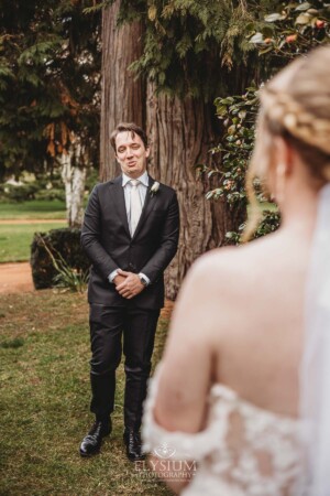 A groom smiles as he sees his bride for the first time during their private first look