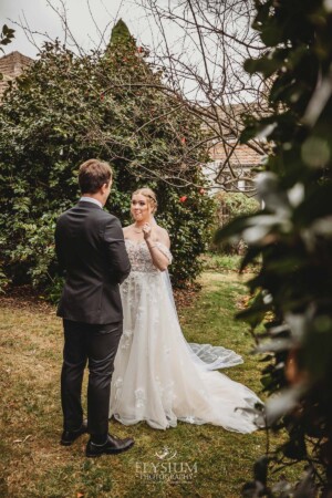 A groom smiles as he sees his bride for the first time during their private first look