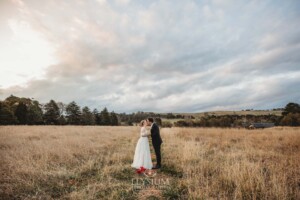 A bride and groom share a kiss as they stand in a field at Bendooley Estate