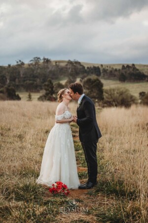 A bride and groom share a kiss as they stand in a field at Bendooley Estate