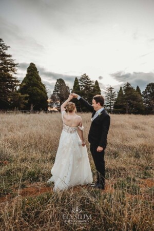 A groom twirls his bride as they dance in a grassy field at Bendooley Estate