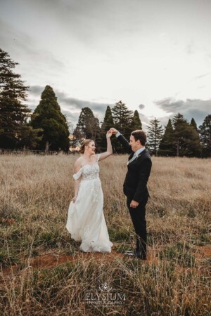 A groom twirls his bride as they dance in a grassy field at Bendooley Estate