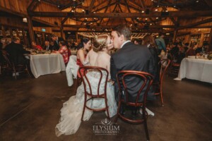 A bride and groom share a kiss at their wedding table in the Bendooley Estate Book Barn