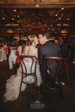 A bride and groom share a kiss at their wedding table in the Bendooley Estate Book Barn