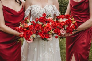 Bridal bouquet details of bunches of bright red florals held by the bride and bridesmaids