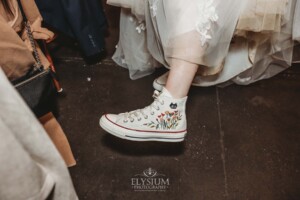 A bride shows off her wedding Converse shoes