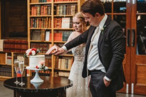 A bride and groom cut into their wedding cake during the reception at Bendooley Book Barn