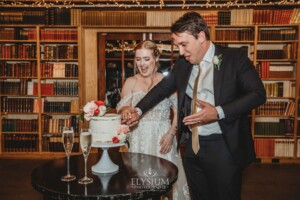 A bride and groom cut into their wedding cake during the reception at Bendooley Book Barn