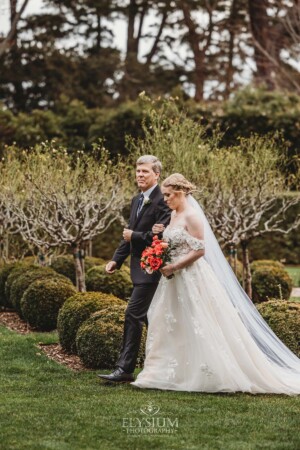 A bride walks down the aisle to greet her groom during their outdoor wedding ceremony