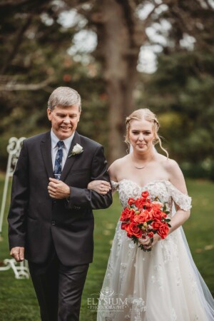 A bride walks down the aisle to greet her groom during their outdoor wedding ceremony