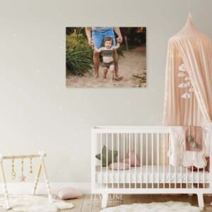 A wall art print displaying baby photo hangs in a baby's room above the cot