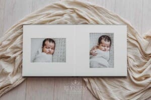 A photo album lays open displaying images from a newborn photoshoot