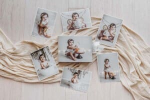 A photo box with prints displaying images from a baby's cake smash photoshoot