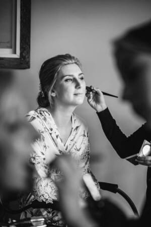 A makeup artist brushes a brides face as she prepares for a wedding ceremony at Camden Valley Inn