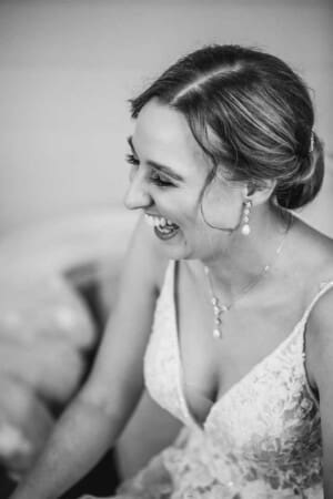 A black and white photograph of a bride having a joyous laugh before leaving for her wedding