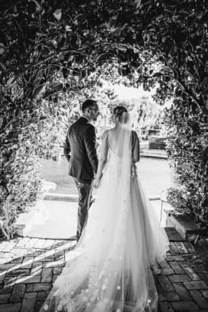 A black and white photo of a couple standing in a leafy arch after their Burnham Grove ceremony
