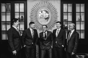 A groom and his groomsmen stand together laughing during prep at Burnham Grove