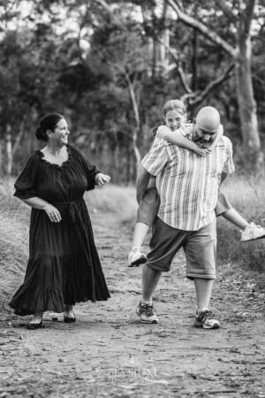 A family walk along a bush trach as the dad carries his daughter on his back
