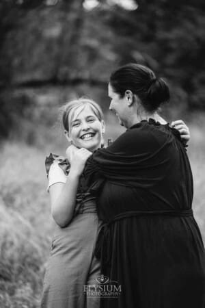 A mother and daughter cuddle as they spin in a grassy field