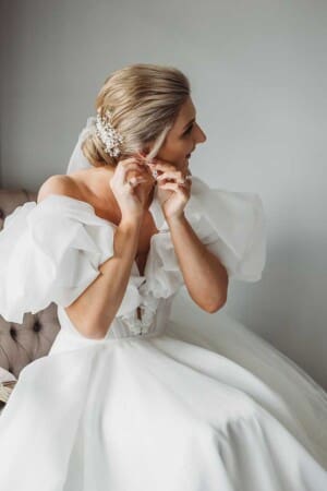 A bride puts on her earings before the wedding ceremony at Camden Valley Inn